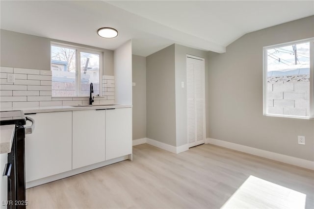 kitchen with white cabinetry, sink, a wealth of natural light, and tasteful backsplash