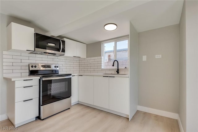 kitchen with appliances with stainless steel finishes, tasteful backsplash, white cabinetry, sink, and light hardwood / wood-style floors