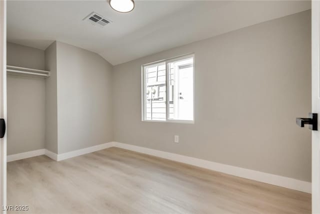 unfurnished bedroom with vaulted ceiling, light hardwood / wood-style floors, and a closet