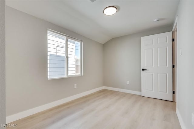 unfurnished room featuring lofted ceiling and light wood-type flooring