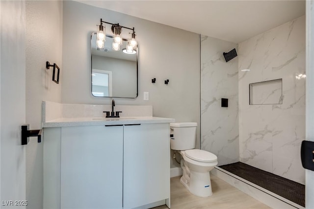 bathroom featuring vanity, wood-type flooring, toilet, and a tile shower