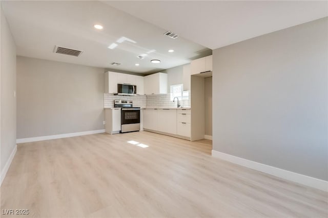 kitchen featuring sink, white cabinetry, tasteful backsplash, light wood-type flooring, and stainless steel appliances