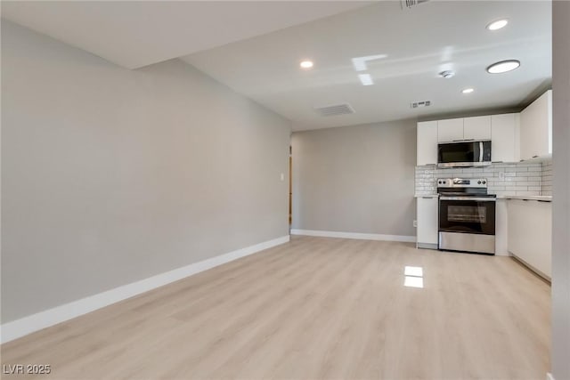 kitchen with white cabinetry, stainless steel appliances, decorative backsplash, and light wood-type flooring