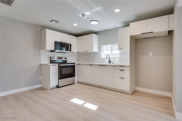 kitchen featuring stainless steel appliances, white cabinetry, sink, and backsplash