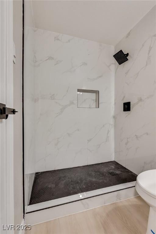 bathroom featuring a tile shower and toilet