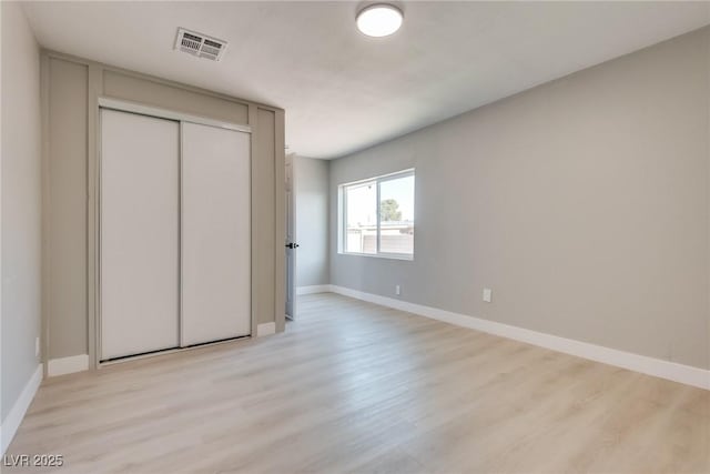 unfurnished bedroom featuring light hardwood / wood-style flooring and a closet