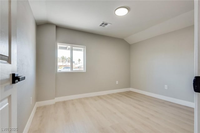 unfurnished room featuring vaulted ceiling and light wood-type flooring