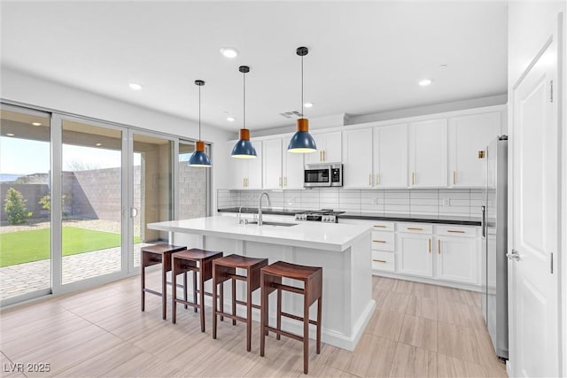 kitchen featuring decorative backsplash, white cabinets, and stainless steel appliances