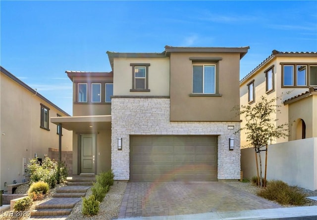 view of front facade with stone siding, a garage, fence, stucco siding, and driveway