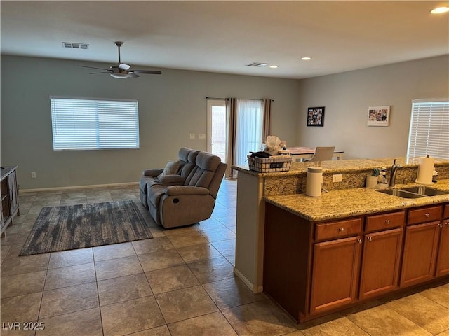 kitchen featuring light stone counters, sink, ceiling fan, and light tile patterned flooring