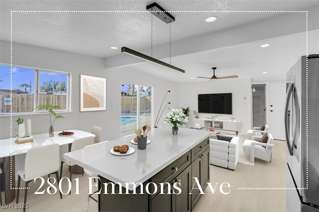 kitchen with fridge, plenty of natural light, a kitchen island, and a textured ceiling