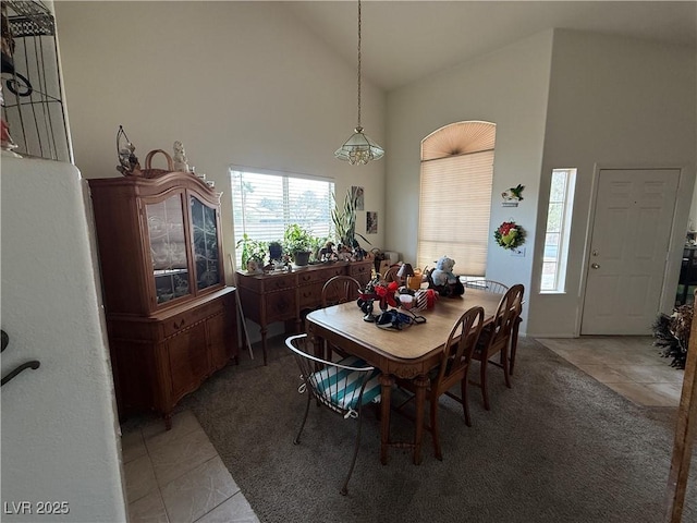 tiled dining area featuring high vaulted ceiling