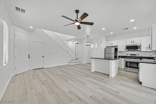 kitchen with pendant lighting, sink, light hardwood / wood-style flooring, appliances with stainless steel finishes, and white cabinetry