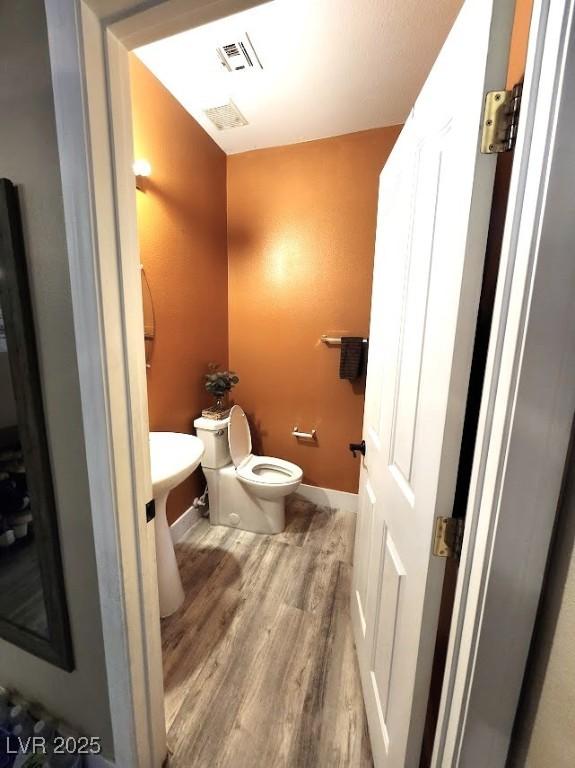 bathroom with wood-type flooring and toilet