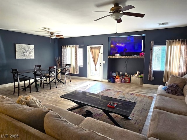 living room with ceiling fan, light hardwood / wood-style floors, and a wealth of natural light