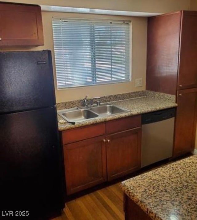 kitchen featuring sink, light hardwood / wood-style flooring, dishwasher, and black fridge