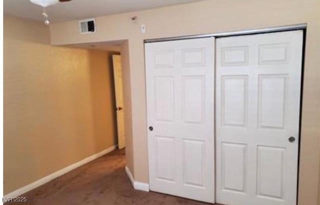 unfurnished bedroom with dark carpet and a closet