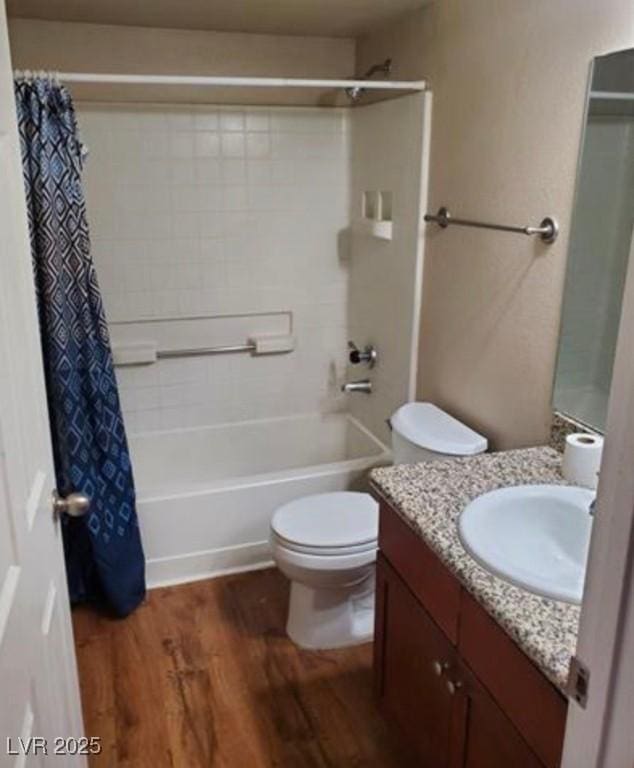 full bathroom featuring wood-type flooring, shower / tub combo, vanity, and toilet