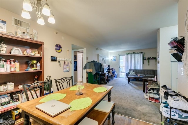 carpeted dining area featuring an inviting chandelier