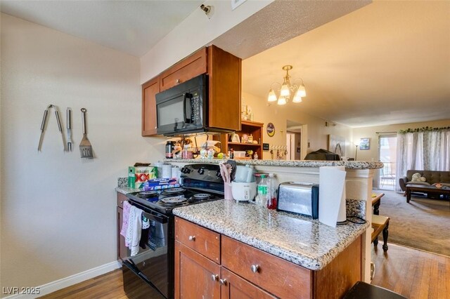 kitchen featuring light hardwood / wood-style floors, light stone countertops, black appliances, kitchen peninsula, and a chandelier