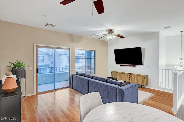 living room with ceiling fan with notable chandelier and hardwood / wood-style floors