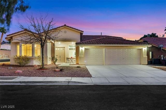 view of front of property with concrete driveway, a tiled roof, a garage, and stucco siding