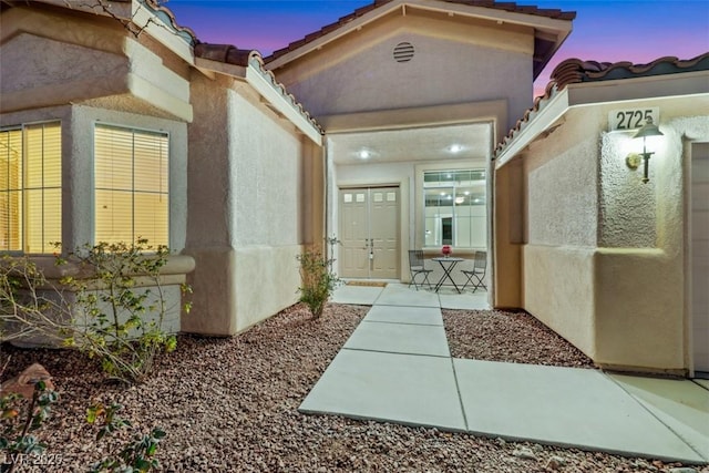 exterior entry at dusk featuring stucco siding