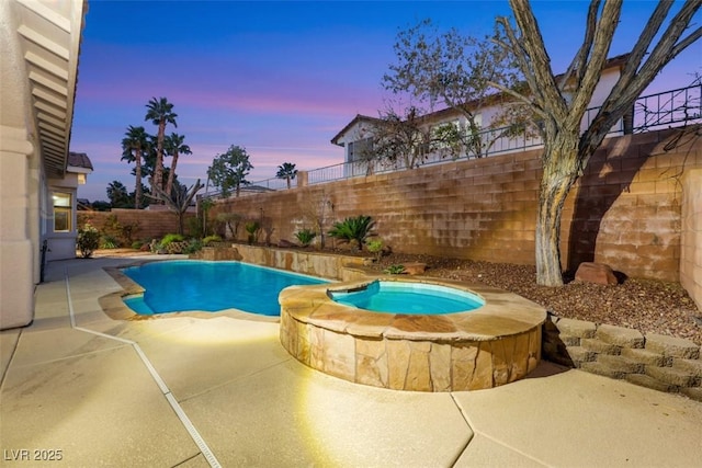 pool at dusk featuring an in ground hot tub and a patio