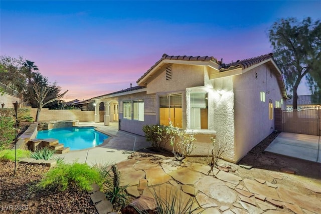 back of property with a patio, a fenced backyard, a fenced in pool, and stucco siding