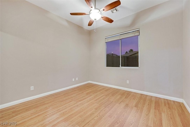 empty room with ceiling fan, visible vents, baseboards, and wood finished floors