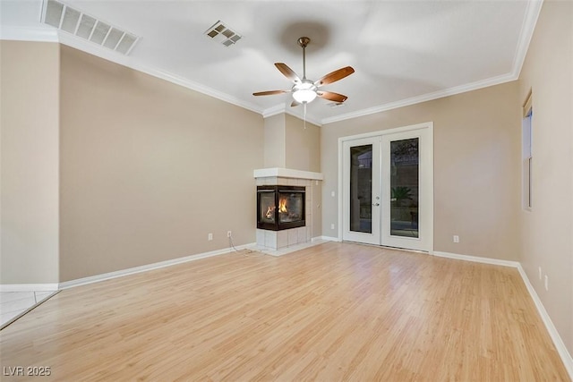 unfurnished living room featuring a fireplace, light hardwood / wood-style flooring, ornamental molding, ceiling fan, and french doors