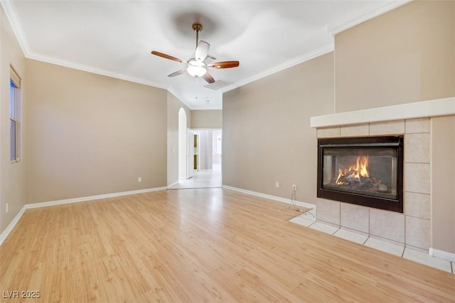 unfurnished living room featuring a tile fireplace, ornamental molding, ceiling fan, and light hardwood / wood-style floors