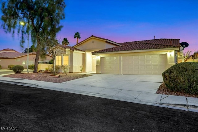 mediterranean / spanish-style house featuring stucco siding, an attached garage, and driveway