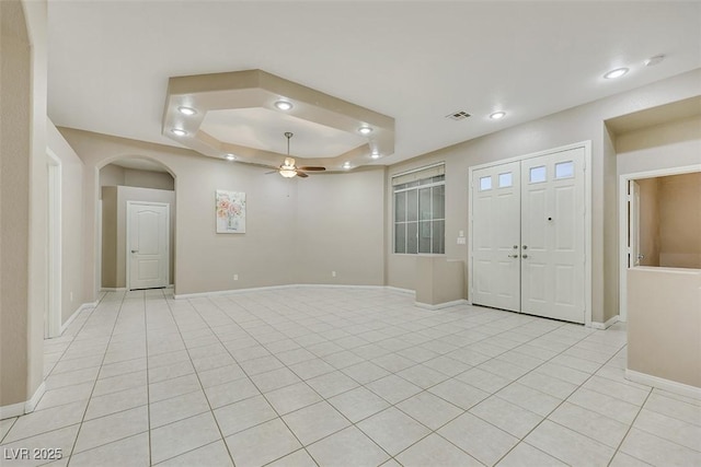 empty room featuring light tile patterned floors, ceiling fan, and a tray ceiling