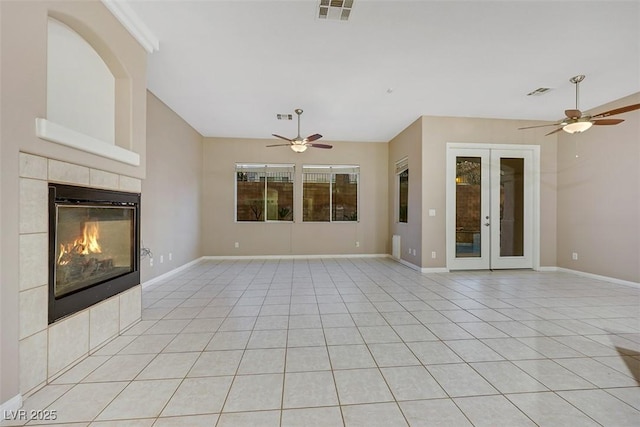 unfurnished living room featuring french doors, ceiling fan, light tile patterned flooring, and a tile fireplace