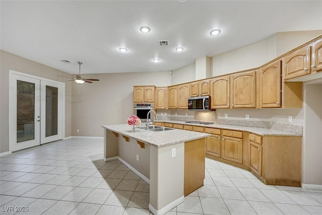 kitchen with appliances with stainless steel finishes, an island with sink, sink, light tile patterned floors, and french doors