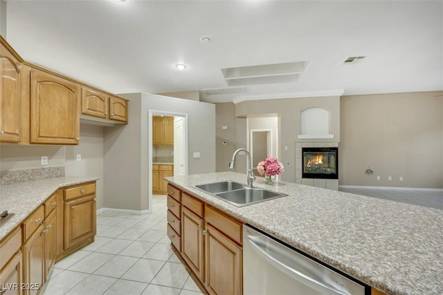 kitchen with stainless steel dishwasher, a fireplace, sink, and light tile patterned floors