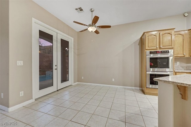 kitchen with light brown cabinetry, double oven, light tile patterned floors, ceiling fan, and french doors