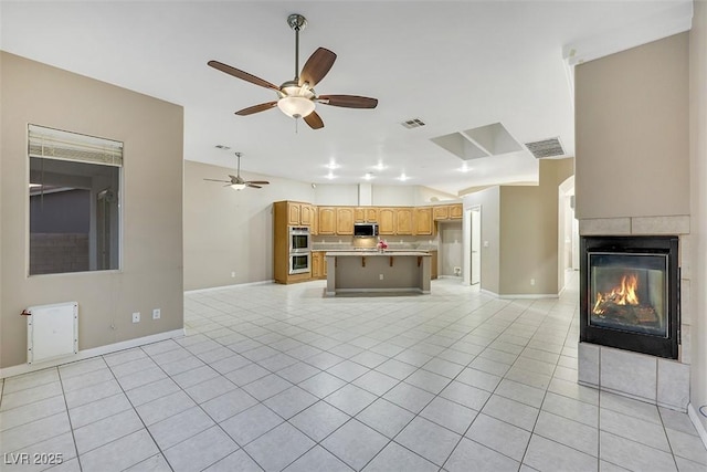 unfurnished living room featuring light tile patterned flooring, ceiling fan, and a tile fireplace