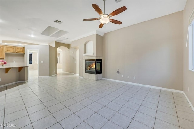 unfurnished living room featuring a fireplace, ceiling fan, and light tile patterned flooring