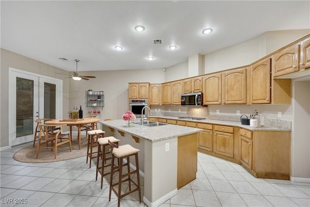 kitchen with visible vents, a kitchen bar, a sink, french doors, and appliances with stainless steel finishes