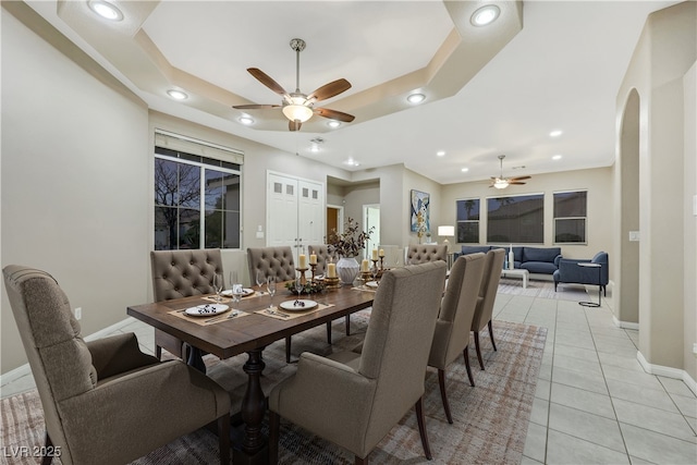 dining area with arched walkways, recessed lighting, a raised ceiling, and light tile patterned flooring