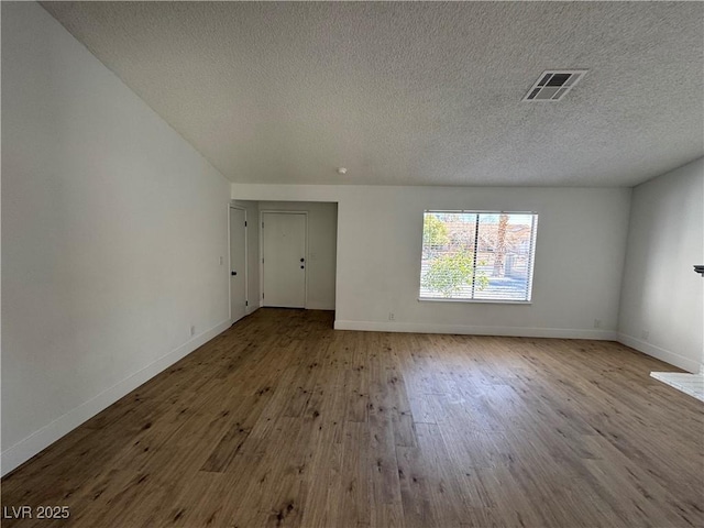 unfurnished room featuring visible vents, a textured ceiling, light wood-style flooring, and baseboards