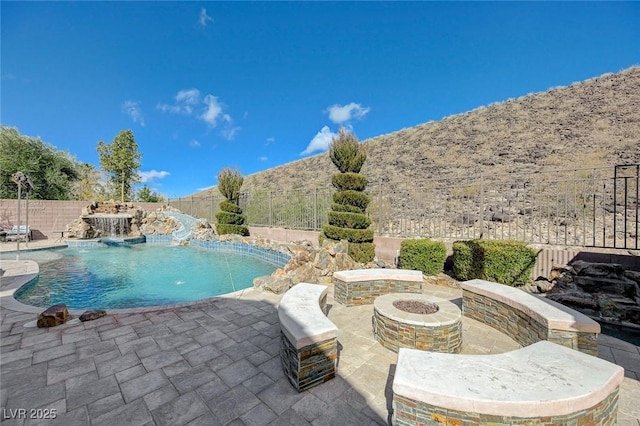 view of swimming pool featuring pool water feature, a patio area, and a fire pit