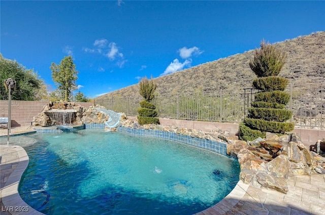 view of pool featuring pool water feature, a water slide, and a mountain view