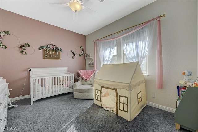 carpeted bedroom featuring a nursery area and ceiling fan