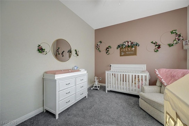 bedroom with a nursery area, vaulted ceiling, and dark colored carpet