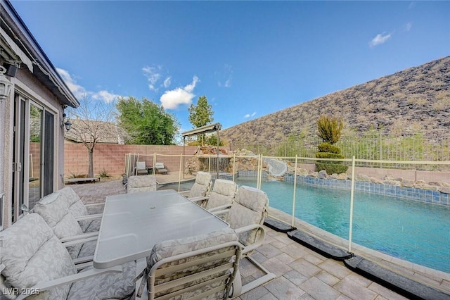 view of pool featuring a water slide, a mountain view, and a patio area