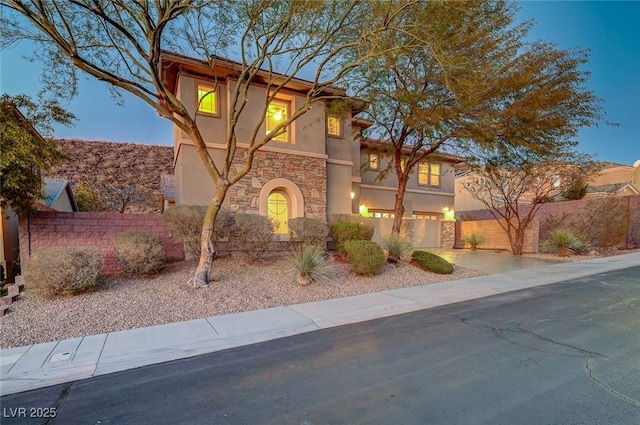 view of front of home featuring stucco siding, stone siding, a garage, and fence