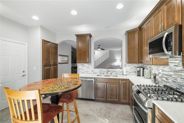 kitchen featuring sink, decorative backsplash, stainless steel appliances, and ceiling fan